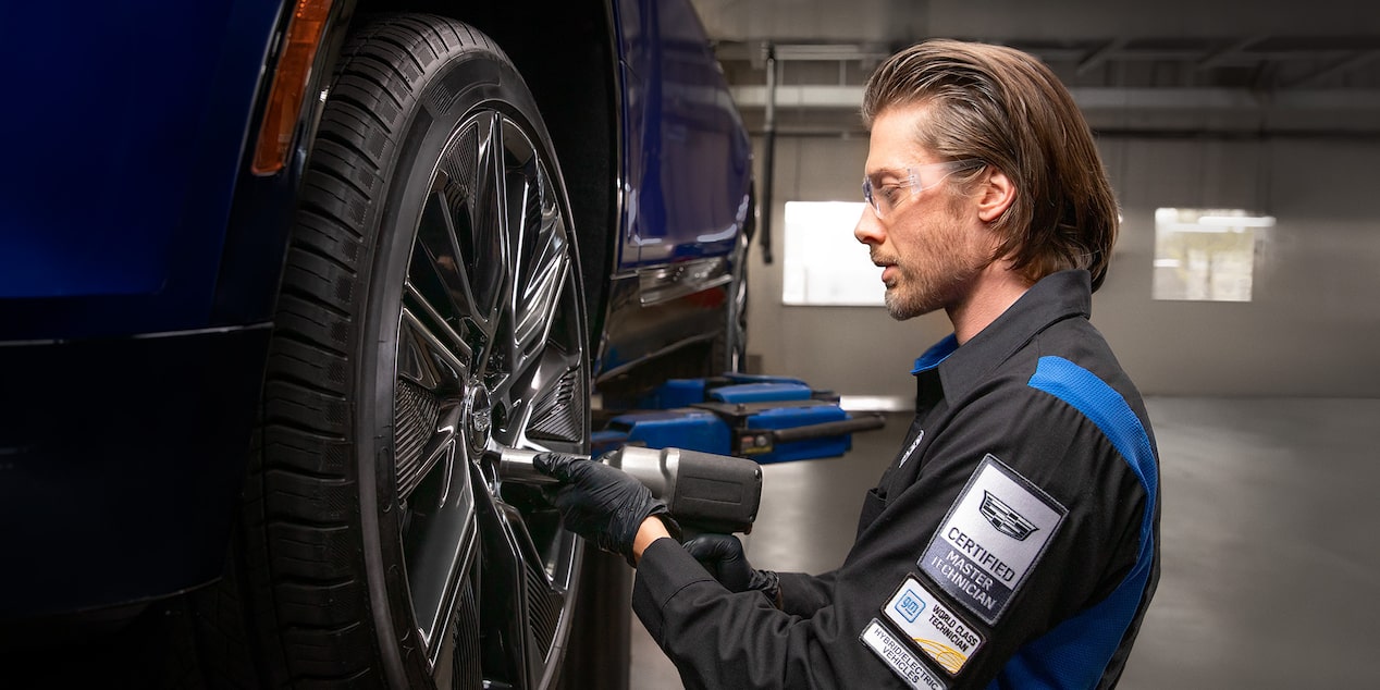 A Technician Is Drilling Screws in a Wheel of a Blue Vehicle Suspended in the Air