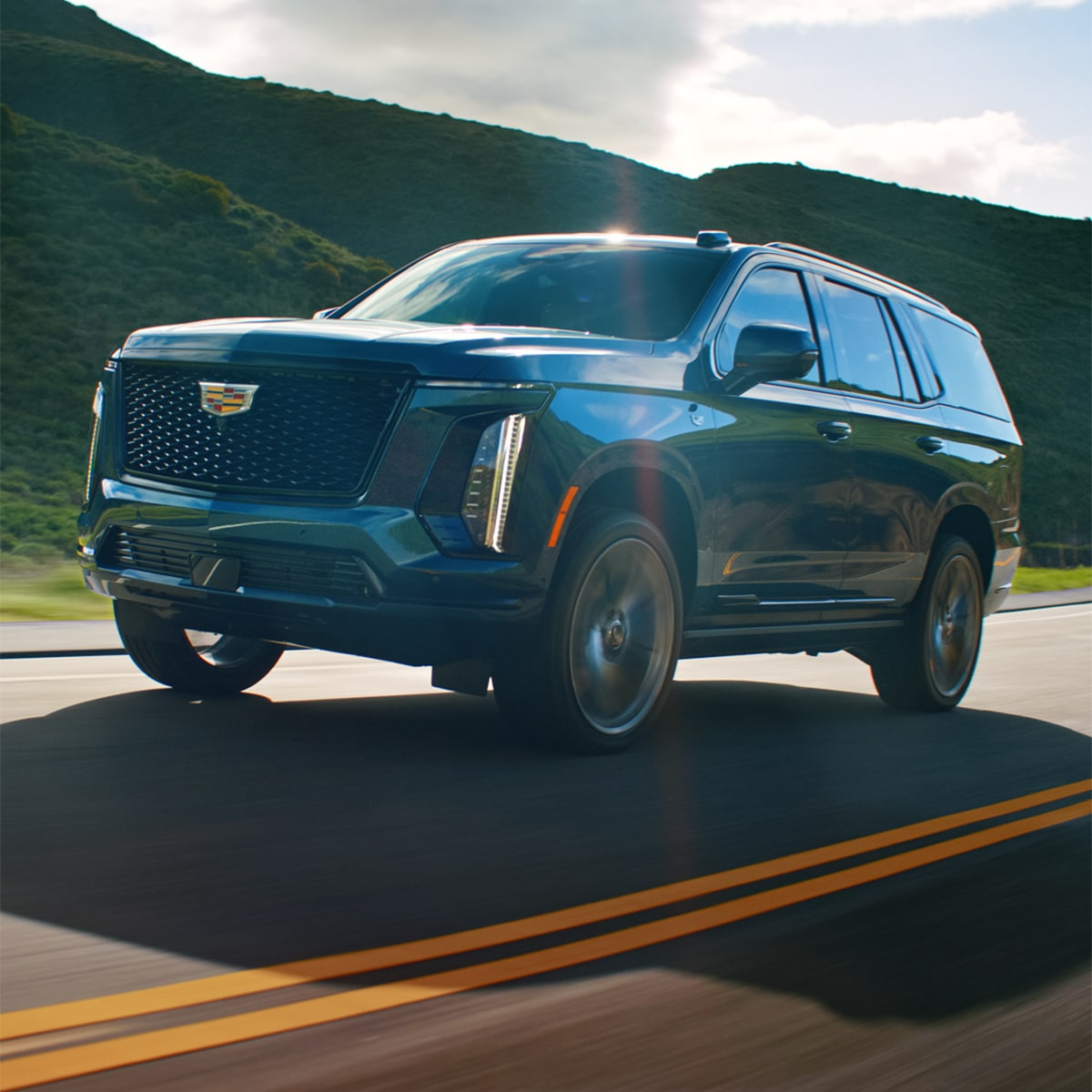 Three-quarters View of the Cadillac Escalade Driving Down a Road near the Mountains