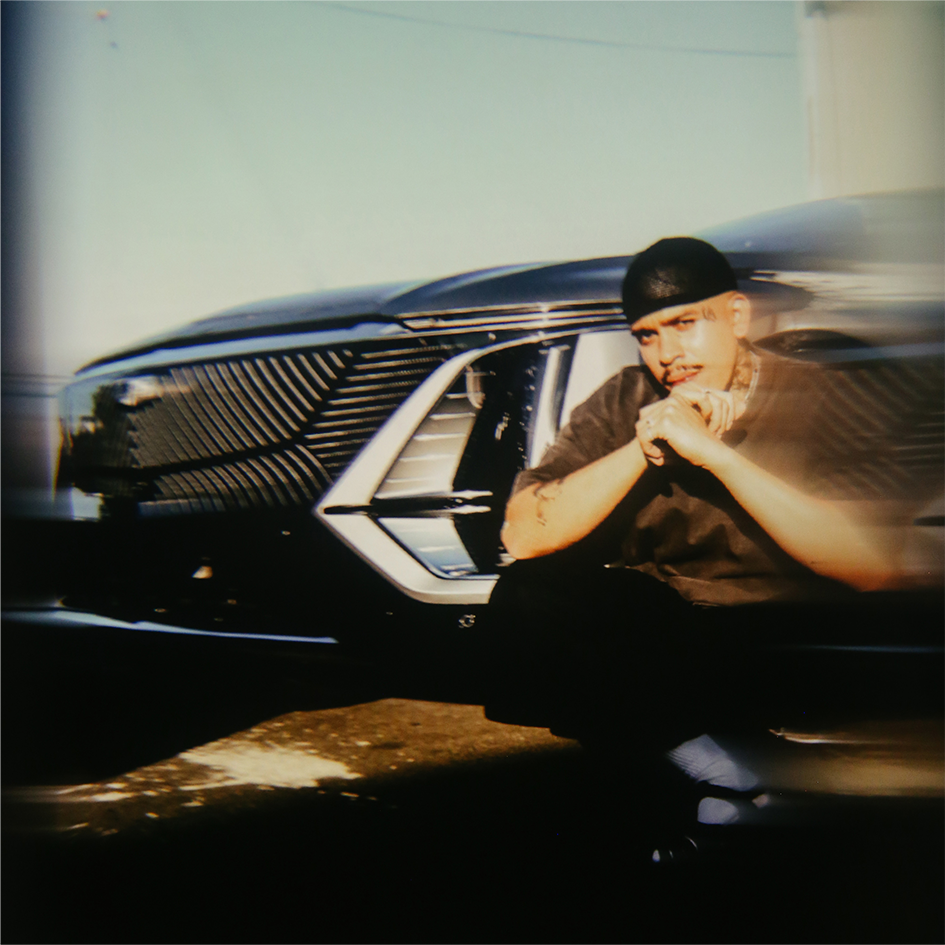 Oakland Artist Esteban Samayoa Squatting in Front of a Cadillac LYRIQ