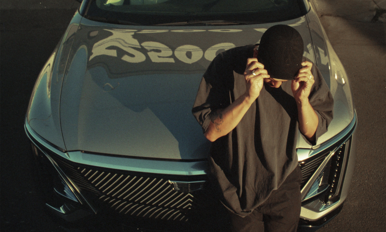 Oakland Artist Esteban Samayoa Leaning on the Front of a Parked Cadillac LYRIQ