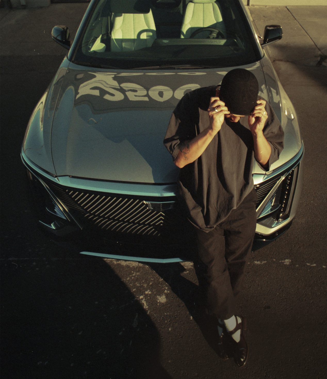 Oakland Artist Esteban Samayoa Leaning on the Front of a Parked Cadillac LYRIQ