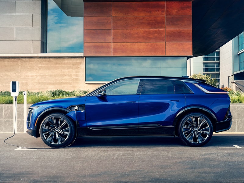 A Side Profile View of a Blue Cadillac LYRIQ Charging Outside a Modern Building