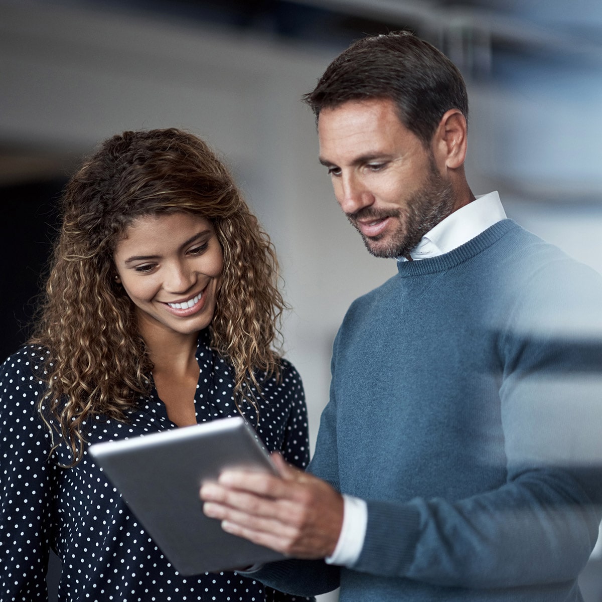 Primer plano de una mujer y un hombre mirando un iPad y sonriendo