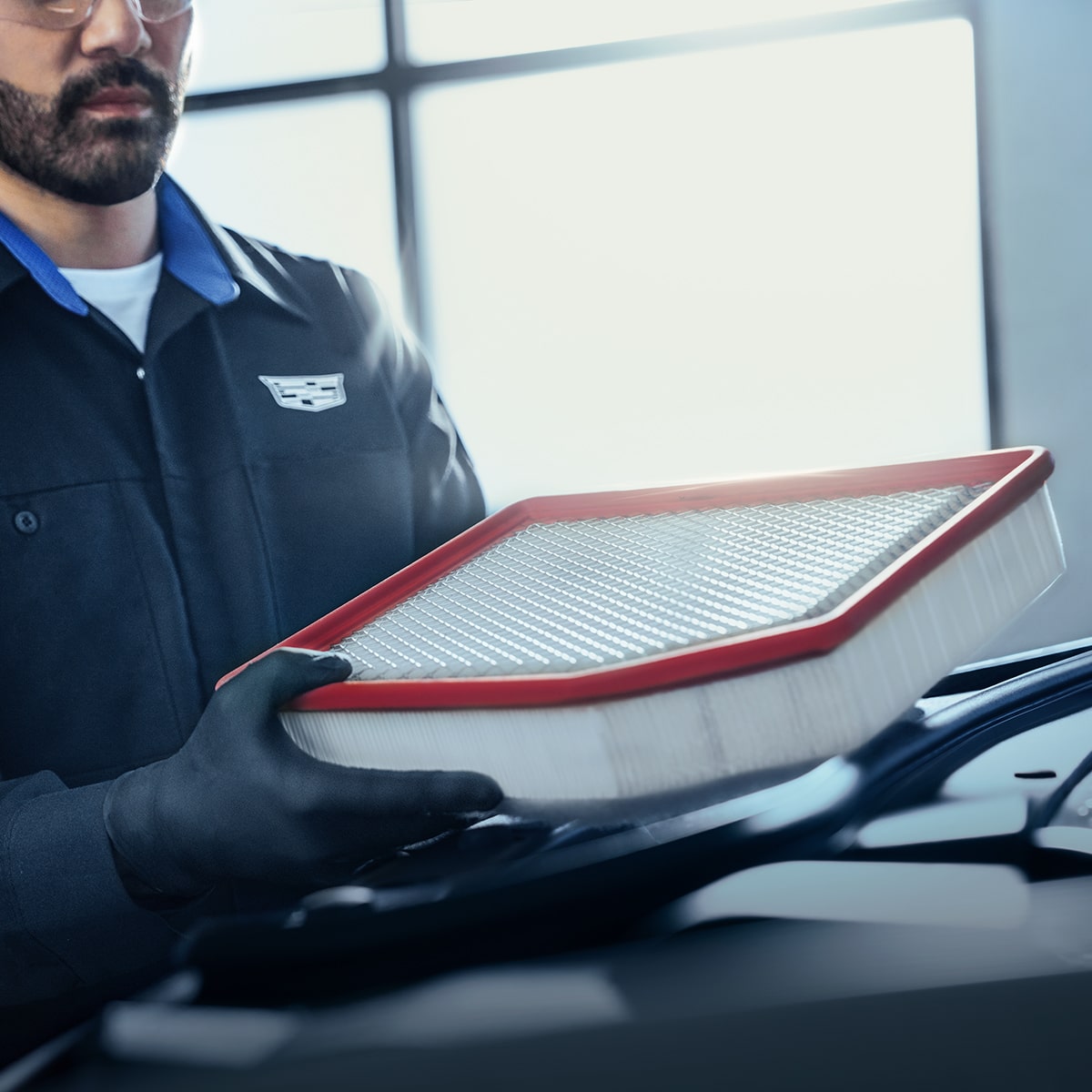 Primer plano de un miembro del equipo de servicio de Cadillac sujetando un filtro de aire