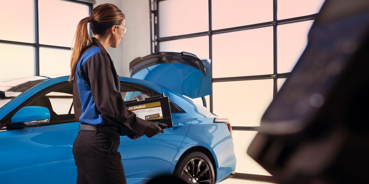 Cadillac Technician Carrying an ACDelco Gold Battery to Install in Nearby Vehicle