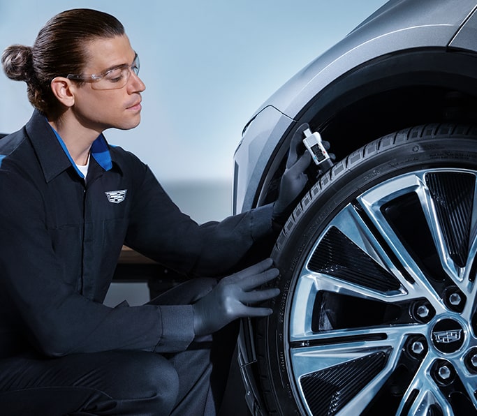 Cadillac Certified Service Technician Attaching Jumper Cables on a Vehicle