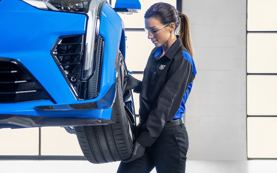 Técnico de Cadillac parado enfrente de un vehículo Cadillac inspeccionando una hoja de información del vehículo