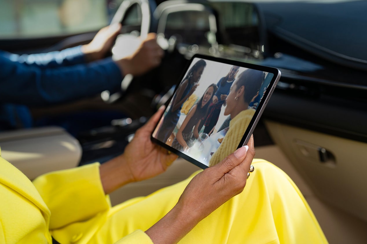 Primer plano de una pasajera de la fila delantera sosteniendo y mirando un Ipad en un Cadillac