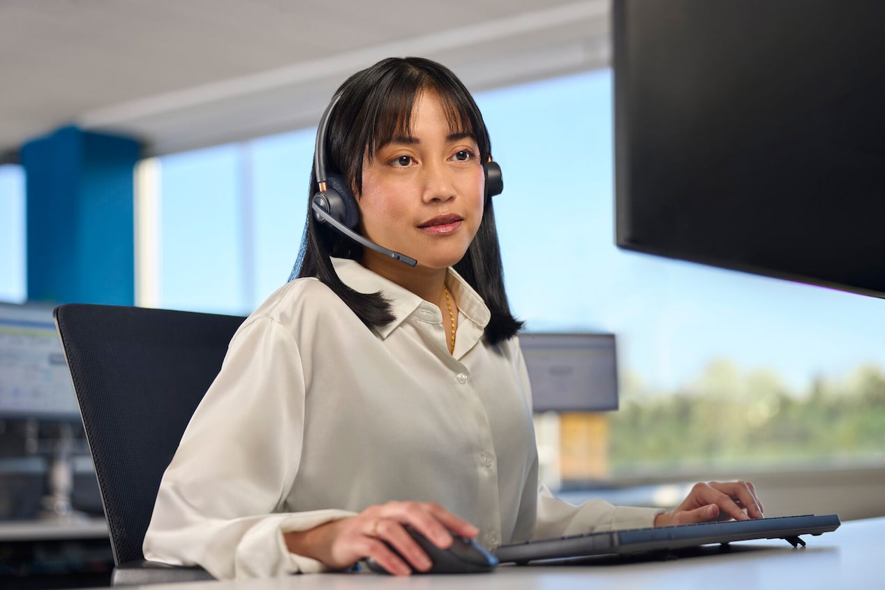 Una empleada de OnStar con auriculares trabaja frente a una computadora en su oficina