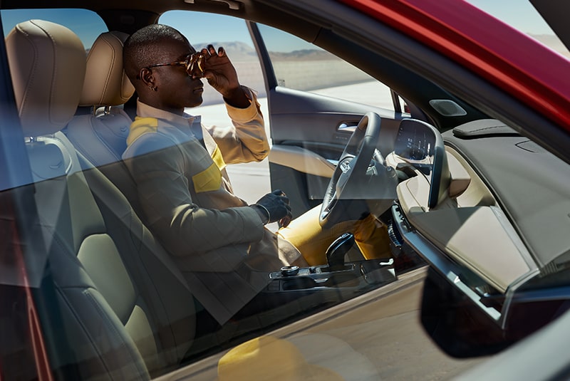 Side View of a Man inside a Red Cadillac in the Drivers Seat Seen from Outside the Vehicle