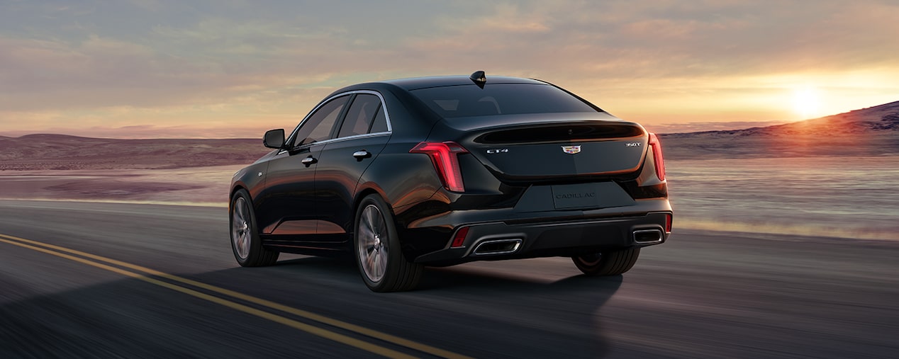 Three Quarters Rear View of a Black Cadillac Driving Down the Road on a Golden Hour Before Evening