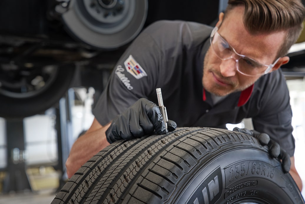 Un experto en protección de Cadillac revisando un neumático