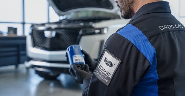 Cadillac Technician Holding a ACDelco Oil Filter Standing Next to a Vehicle