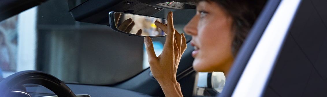 A Woman in Her Cadillac Vehicle Pressing the OnStar Button for Assistance