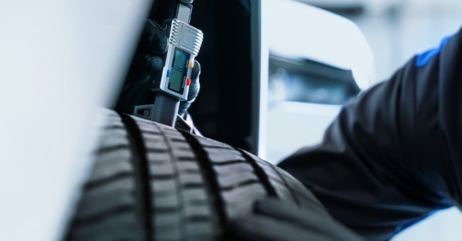 Close-Up of Cadillac Technician Checking Tread Level on a Tire