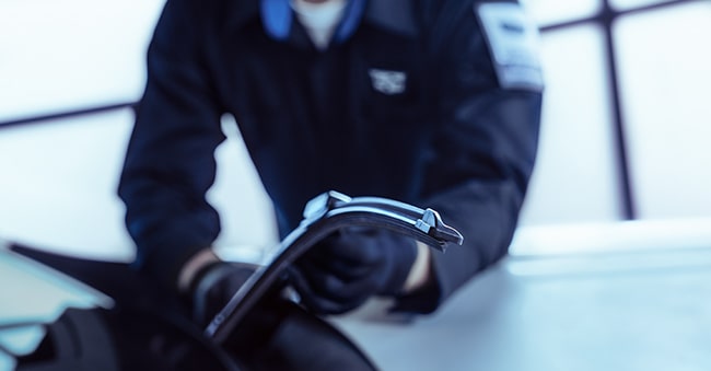 Cadillac Technician Installing New Windshield Wipers on a Vehicle