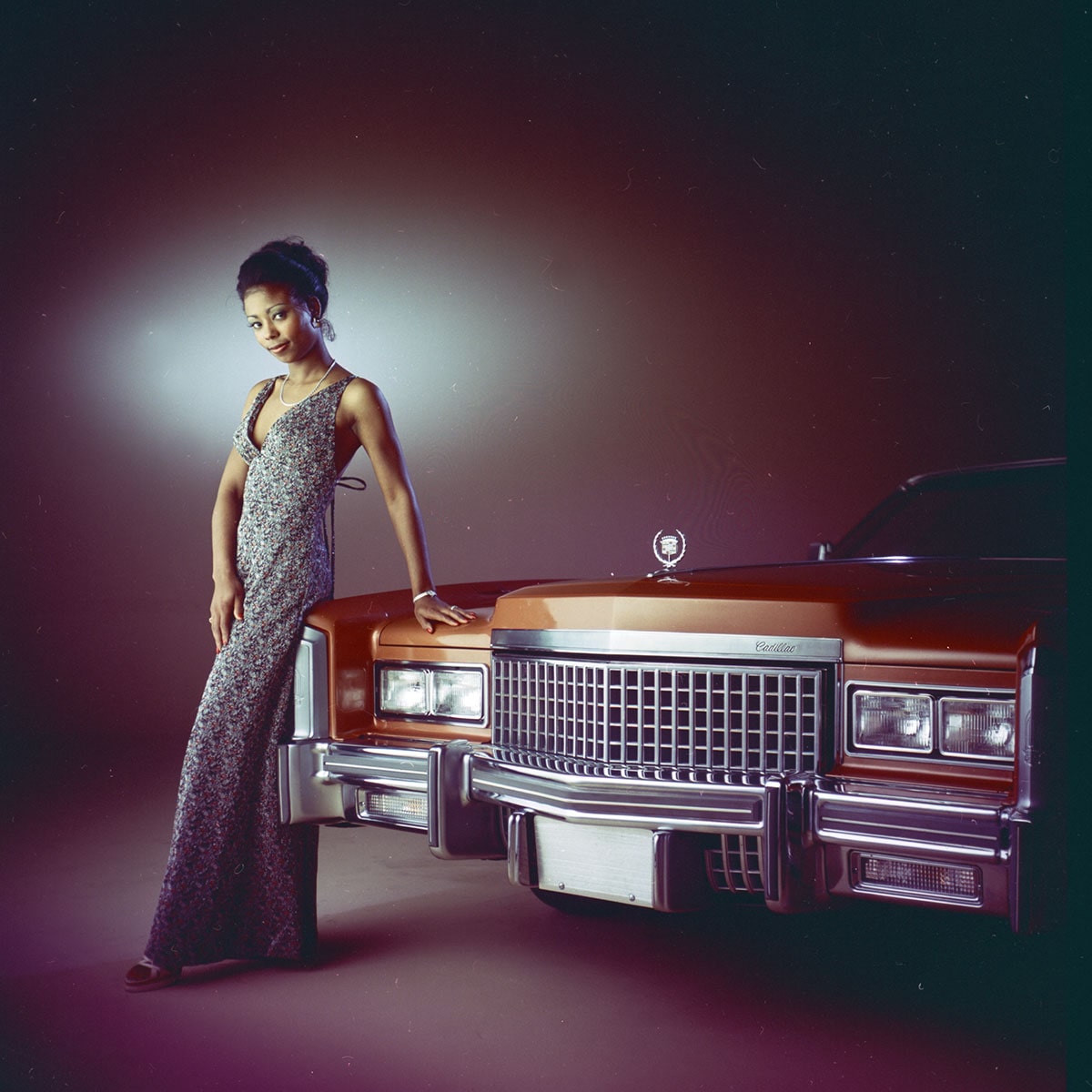 A Fashionably Dressed Woman Standing in Front of a Classic Brown Cadillac