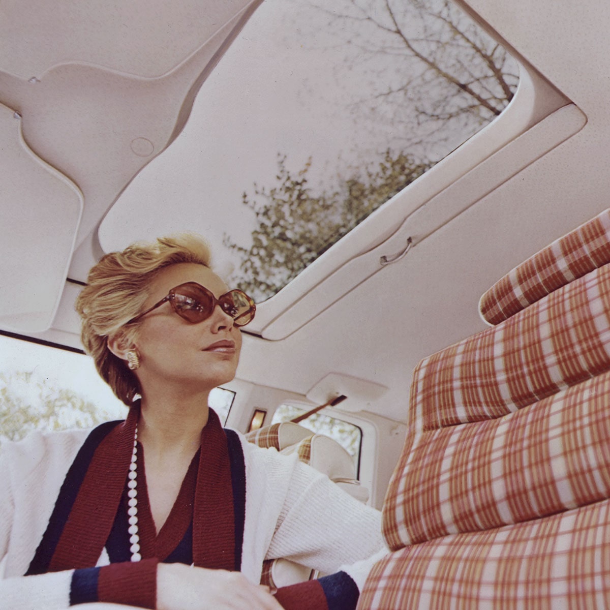 Una mujer sentada en el interior de un Cadillac, vestida con un atuendo elegante