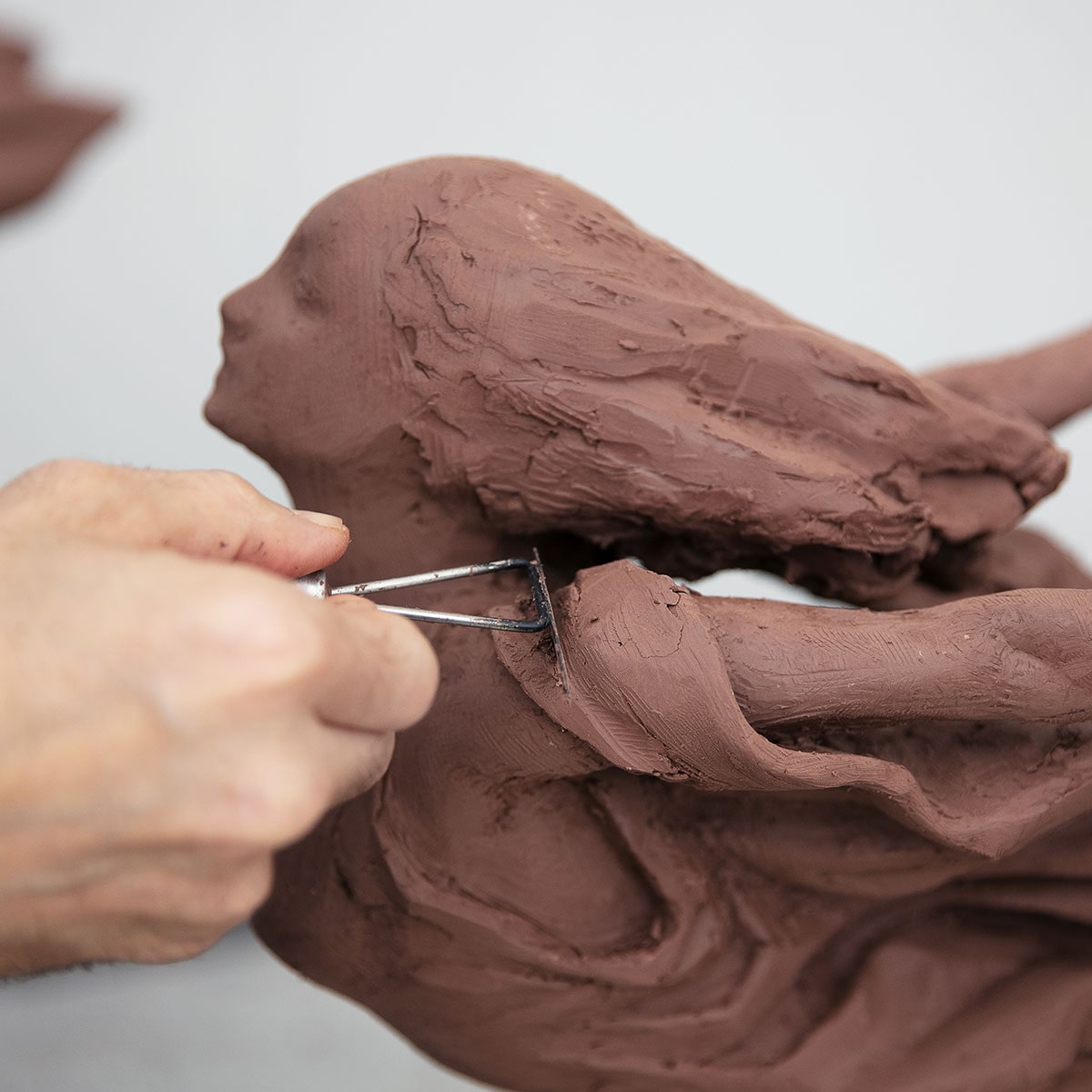 Artist Carving Cadillac Goddess Figure Details Out of Clay