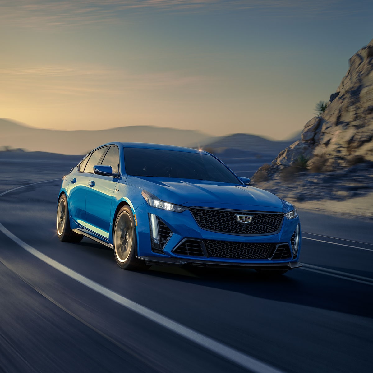 A Blue CT5-V Performance Sedan Racing Around the Curve of a Mountain