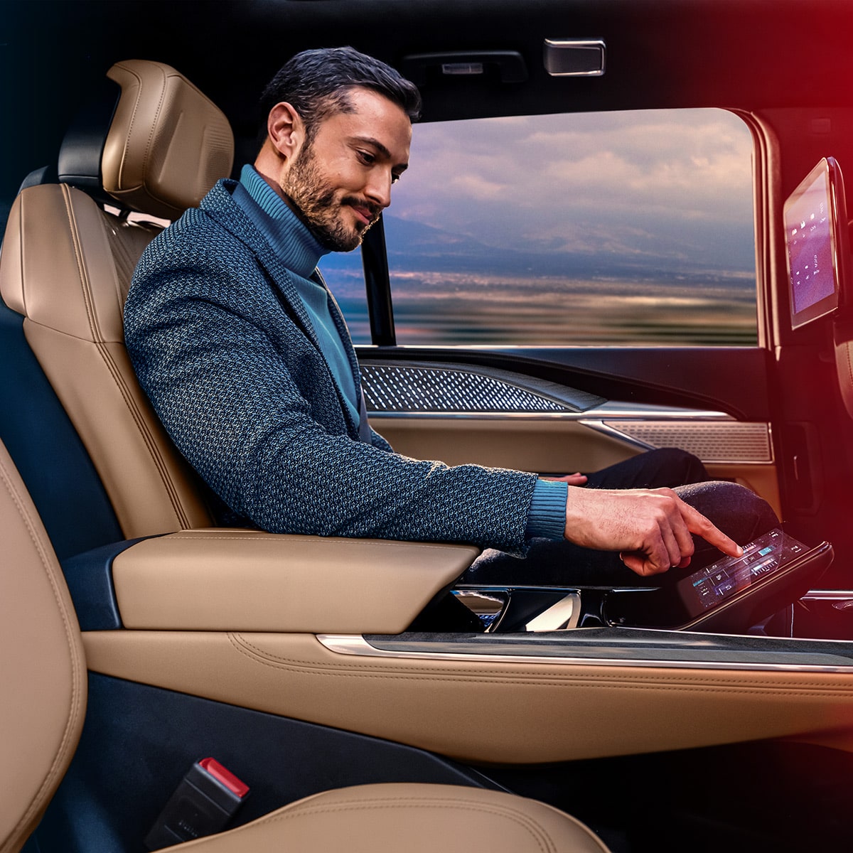 Un hombre utilizando funciones de entretenimiento en el asiento trasero de Cadillac Escalade IQ 2025