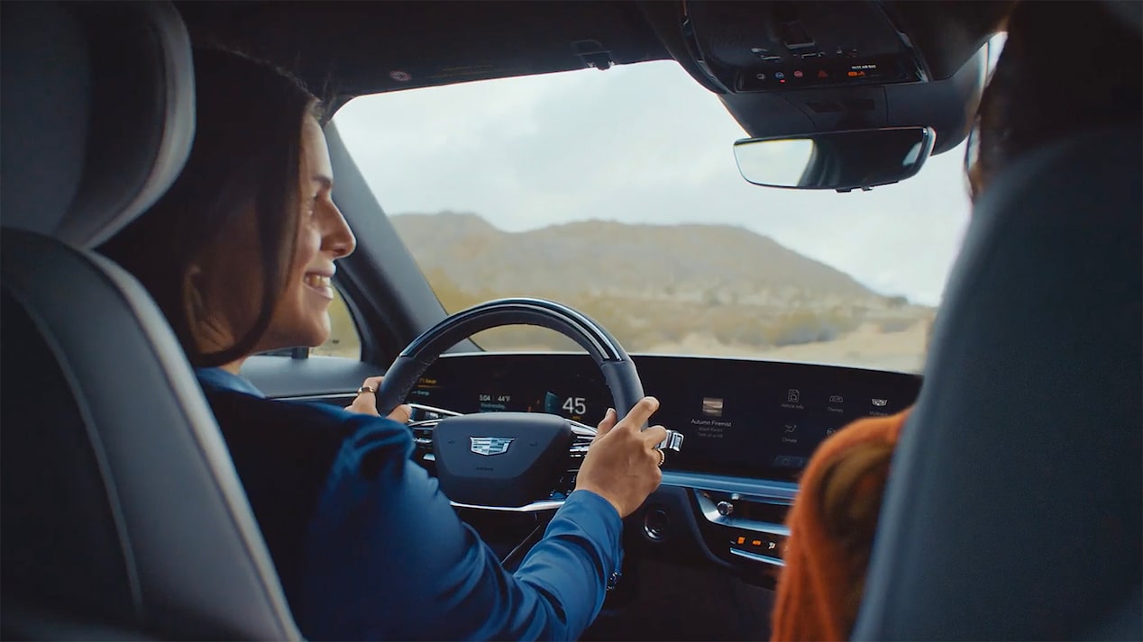 Dos amigas se ríen dentro de su Cadillac LYRIQ mientras atraviesan las montañas