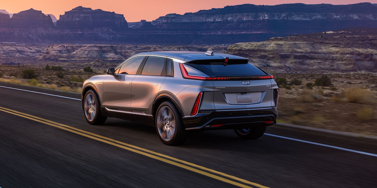 The 2024 LYRIQ Driving on an Open Country Road with a Mountain Backdrop During Sunset