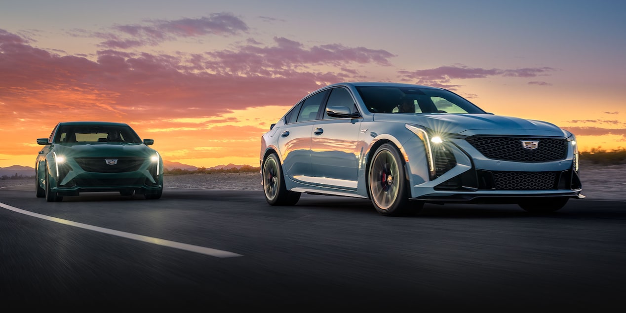 Two 2025 Cadillac CT5-V Sedans Driving on a Road Under an Evening Sky