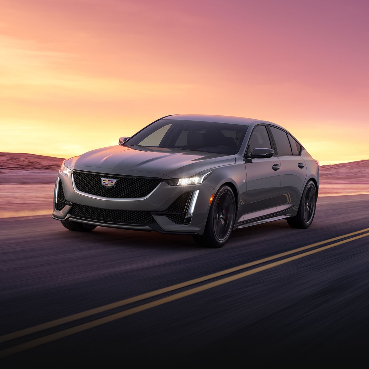 The 2024 Cadillac CT5 Driving Down a Road During Sunset