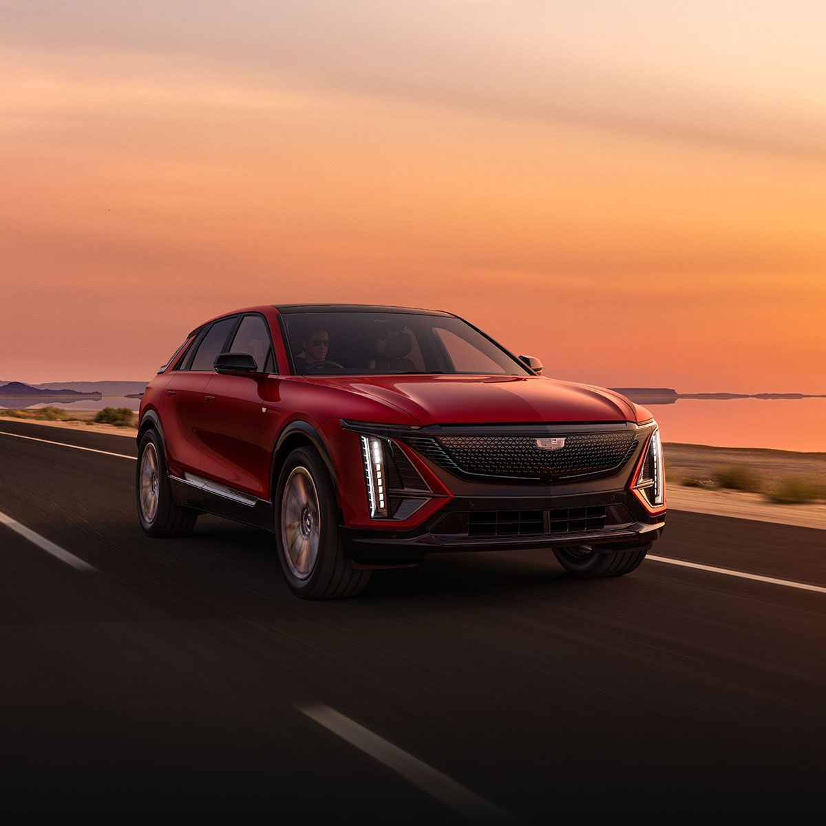 Front View of a Red 2025 Cadillac LYRIQ Cruising Down a Road